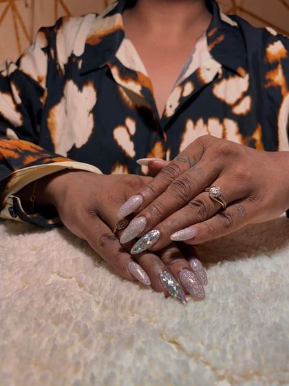 A full-glam look with long, pointed extensions covered in sparkling silver and holographic glitter.