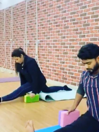 Students working on their Hanumanasana (splits) preparation using blocks for support. This gradual approach helps to open the hips safely.