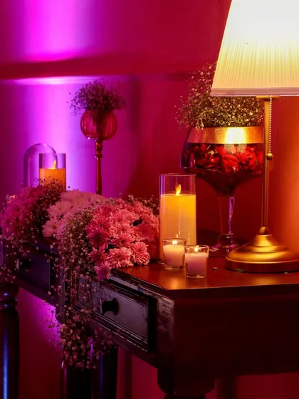An intimate decor detail, combining lush pink flowers, baby's breath, and warm candlelight. These small touches collectively build a rich, luxurious atmosphere.