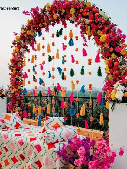For a vibrant Mehndi, I love using a riot of colors. This gorgeous outdoor setup uses a floral arch with hanging tassels against a beautiful skyline view.