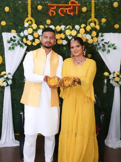 A happy couple posing at their Haldi ceremony, both dressed in coordinated yellow outfits.