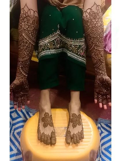 A full bridal set, with intricate mehndi on both hands and feet. The designs are consistent, featuring classic floral and paisley motifs perfect for a traditional wedding.