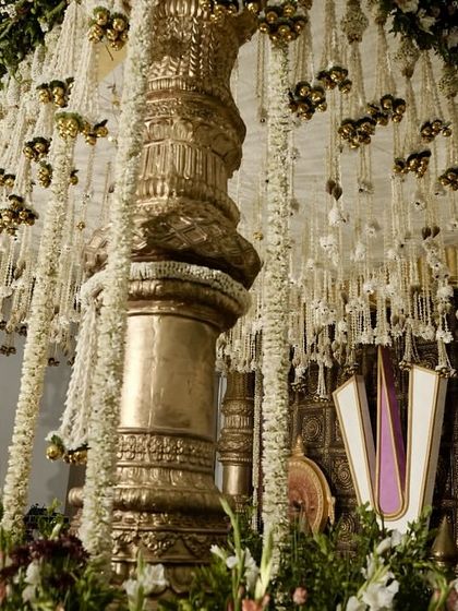 A close-up view of the magnificent temple-style mandap, highlighting the detailed carving on the pillars and the dense floral work.