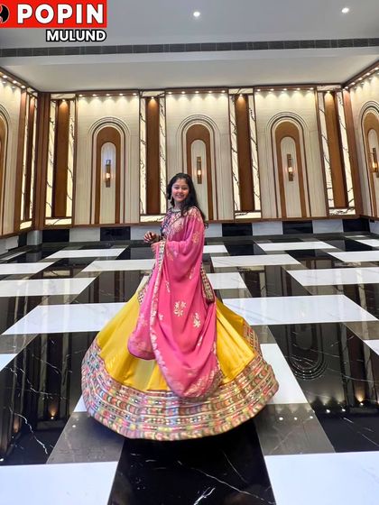 A client looking radiant in a bright yellow lehenga with a contrasting pink dupatta. The grand checkered floor highlights the beautiful flare of the skirt.