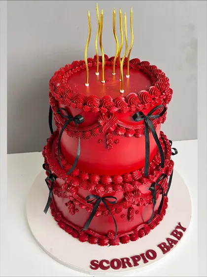 This cake was designed for a client who loves all things bold and dramatic. The deep red buttercream is adorned with intricate, hand-piped vintage details and delicate black ribbons, creating a striking two-tiered cake that is both fierce and elegant.