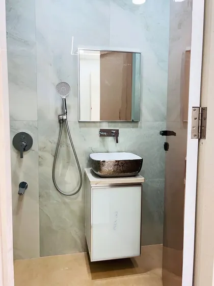 The entrance to the bathroom, showing the compact layout with the vanity, mirror, and shower fixtures.