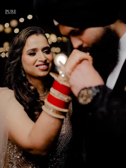 A beautiful, candid moment from a reception party. The groom's gentle kiss on the bride's hand is a classic gesture of love and respect.