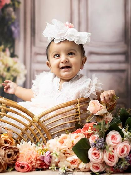 A single portrait of one of the twins, smiling brightly from her basket of flowers.
