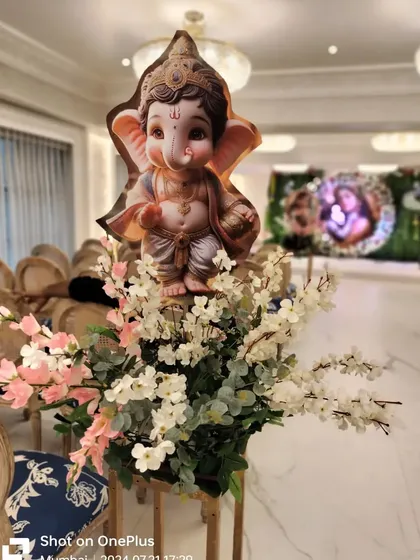 A close-up of a decorative element from a baby shower. This floral arrangement is topped with a cute baby Ganesha cutout, adding a divine and auspicious touch.