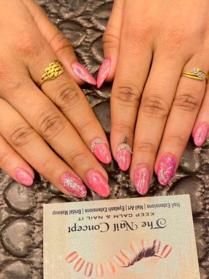 A pretty pink set of almond nails with sparkling details. The design includes a subtle glitter effect and a delicate line of crystals along the cuticle.