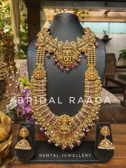 A heavy and ornate bridal set with a large Lakshmi choker and a matching long haram. This is perfect for a bride wanting a grand, traditional look.