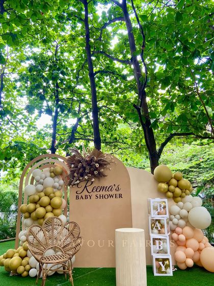 An aesthetically pleasing boho baby shower set against a beautiful natural backdrop. The neutral-toned decor, pampas grass, and peacock chair create a serene and picturesque setting for the mommy-to-be.