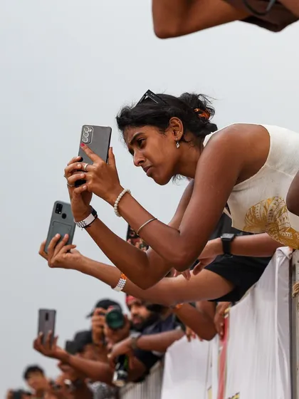 The crowd captures every moment on their phones, leaning over the barriers to get the perfect shot of the action.