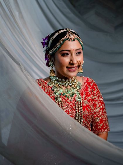 A lovely portrait of the bride, her smile radiant as she peeks from behind a white curtain.