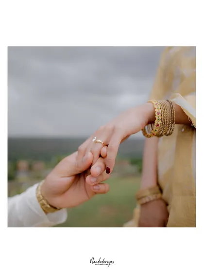 A beautifully composed close-up of a couple holding hands, showcasing the engagement ring and the promise it represents.