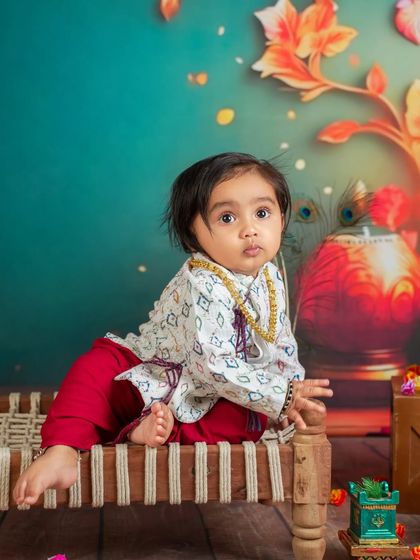 A close-up shot capturing the intricate details of the outfit and the baby's sweet expression against our colorful, festive backdrop.