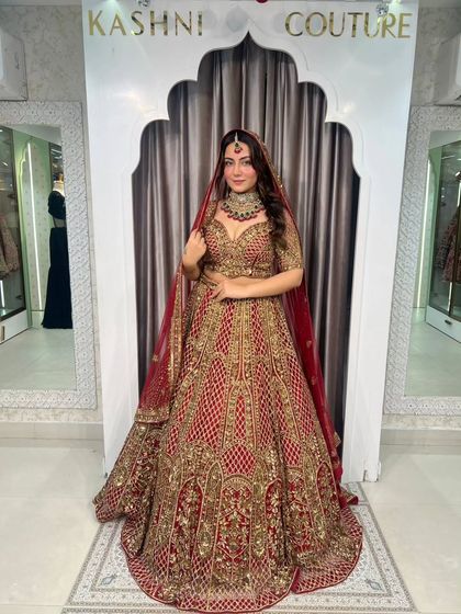 A full-length view of this stunning red and gold bridal lehenga. Notice the intricate hand embroidery and the grand flare, designed to make you feel like a queen.
