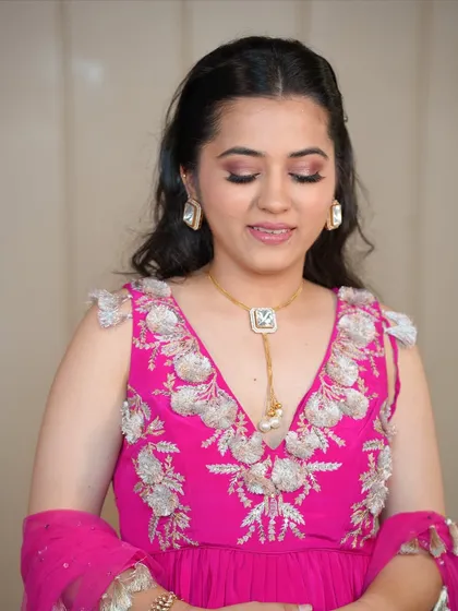This image highlights the complete look, with the soft makeup perfectly complementing the bright pink outfit and elegant jewelry.