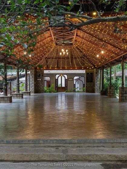 The main hall, with its high, tiled roof and stone pillars, is a grand space for dining and celebrations, shown here lit for an evening event.