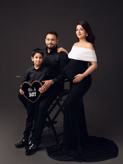 A classic family portrait. The older brother looks so proud, holding an "It's a Boy" sign. It's a beautiful way to announce the gender and include the whole family.