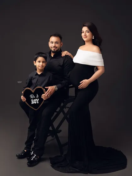 A classic family portrait. The older brother looks so proud, holding an "It's a Boy" sign. It's a beautiful way to announce the gender and include the whole family.