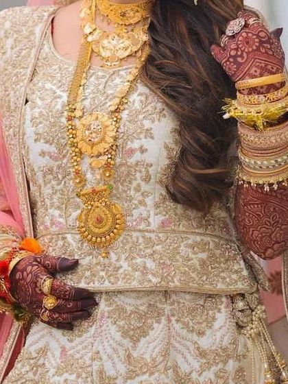 The rich, dark stain of the henna provides a stunning contrast to the bride's elegant white and gold outfit.
