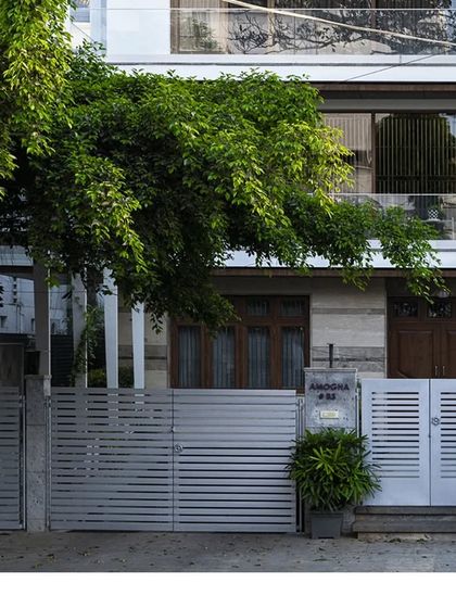 The entrance gate of "Amogha," a modern residence. The design uses clean horizontal lines and a simple color palette that complements the main building's architecture.