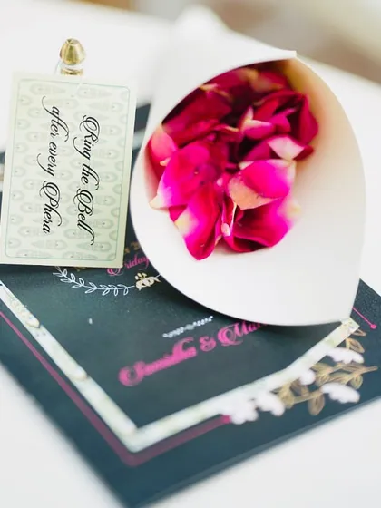 Another interactive guest element. This small card and cone of petals invites guests to participate in the ceremony by ringing a bell after each phera, making them active participants in the couple's union.