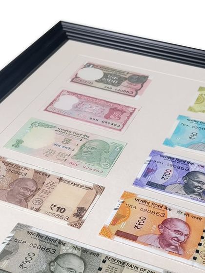 A closer look at the framed currency notes, showing the clean, precise cuts of the mat windows. Using an acid-free off-white matboard prevents the paper notes from yellowing over time.