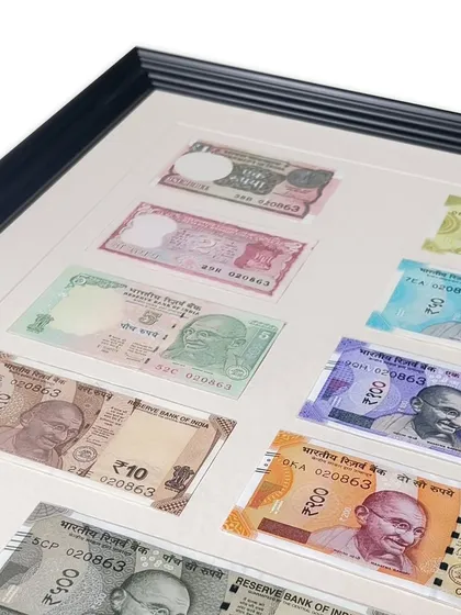 Framing currency notes is a popular request for gifts and collections. For this set of Indian currency, we used an acid-free off-white mat with a V-groove and a classic Philadelphia Black wooden frame for a timeless and elegant presentation.