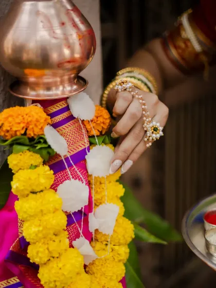 Details make the story. This close-up focuses on the hand-adorning the Gudi with a garland of sugar crystals and flowers, capturing the delicate and meaningful traditions of the festival.