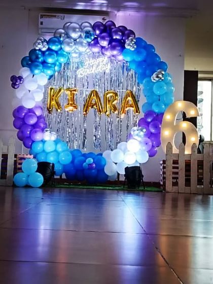 A beautiful ring decoration in shades of blue and purple with a silver tinsel backdrop, perfect for a stylish birthday party.