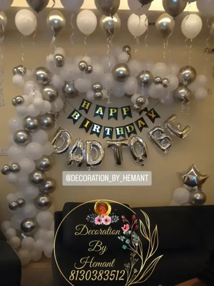 A "Happy Birthday Dad To Be" decoration. This is a great way to celebrate the expecting father, with a silver and white balloon arch and foil letters set up in the living room.