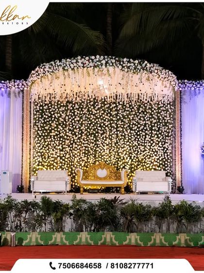 A breathtaking reception stage with a wall of white flowers and a canopy of hanging florals. The golden sofa provides a perfect focal point in this all-white wonderland.