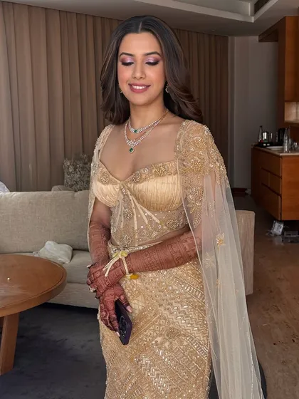 A full view of the soft yet sultry glam look. The golden gown is complemented by warm-toned makeup and elegant, soft curls.