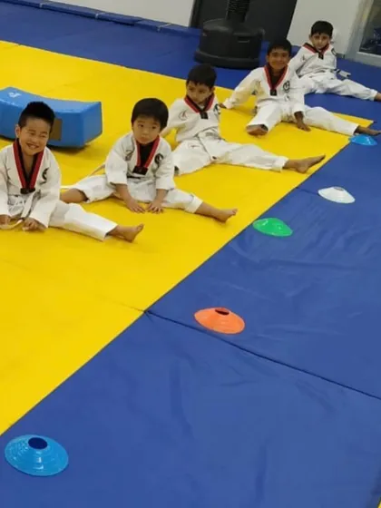 After a rigorous training session, flexibility is key. Our young students work on their splits and stretches, an essential part of Taekwondo that improves range of motion and prevents injury.