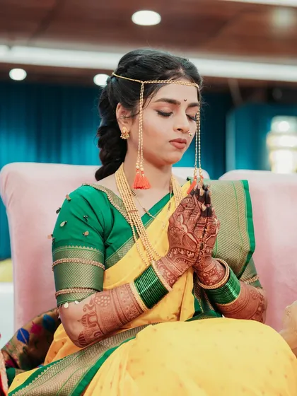 A moment of prayer for the bride during her Haldi ceremony, dressed in a traditional yellow and green saree.