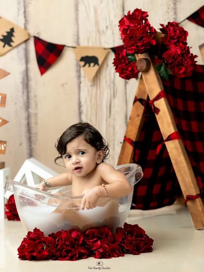 A wider shot of the camping-themed milk bath setup, showing the tent, banner, and other decorative elements.
