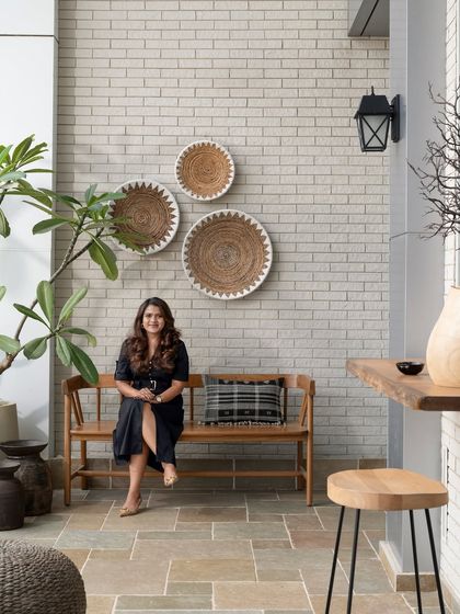 Taking a moment on this beautiful patio, which blends natural materials like stone, wood, and wicker. Creating a seamless transition between indoor and outdoor spaces can bring a sense of calm and openness to a commercial setting, such as a cafe or office terrace.
