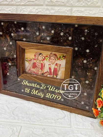 The dark resin teakwood frame, shown from the front to highlight the contrast between the dark background and the wedding photo.
