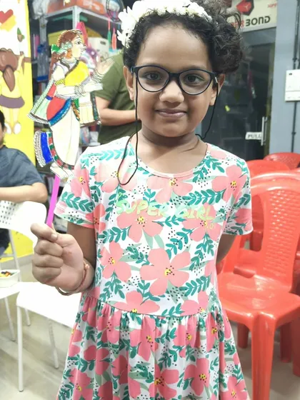 A proud artist with her creation. This young participant is all smiles after finishing her puppet, inspired by the traditional art she just witnessed. These activities help foster creativity and a connection to our heritage.