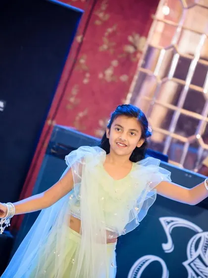 A young girl dancing joyfully at a Mehendi function in her light mint green lehenga. The outfit is designed for comfort and movement.