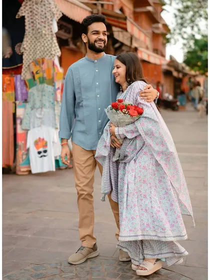 A happy, candid shot of the couple in a Jaipur market, with the bride holding a bouquet of red roses.