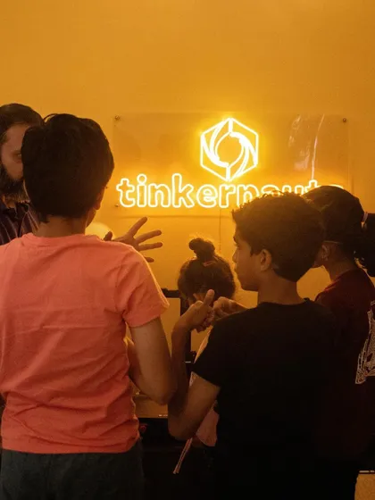 Another shot of students gathered around the Tinkernauts sign, eagerly watching a project being 3D printed.