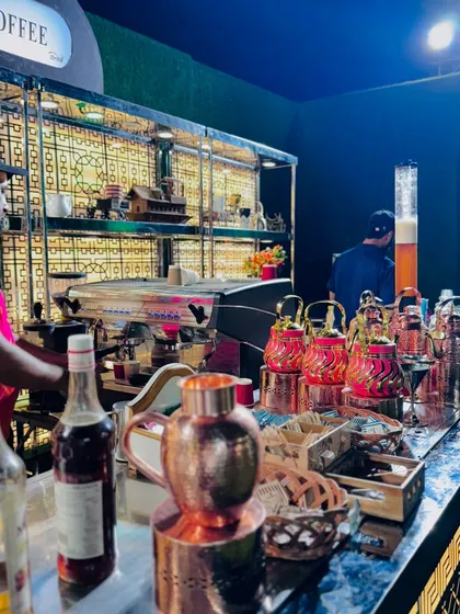 The coffee bar in action, with a barista preparing drinks and a display of elegant copper teapots.