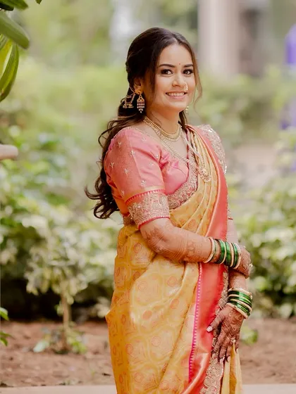 A full-length portrait showcasing her beautiful saree and the soft, flowing hairstyle I created to complement it. The makeup is natural and radiant, perfect for a day wedding.