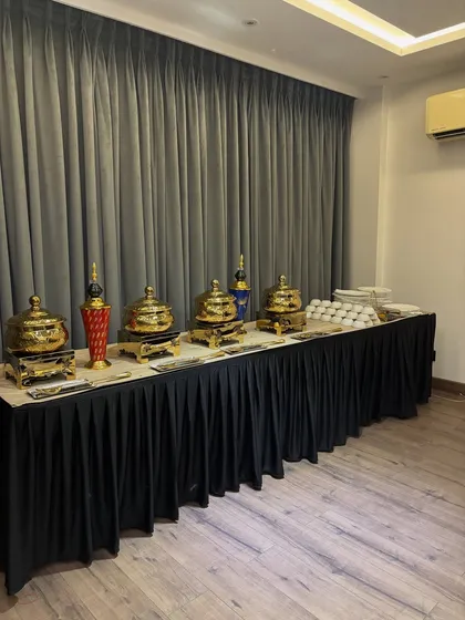 A full view of a classic buffet line with a black table skirt, perfect for corporate events or formal parties.