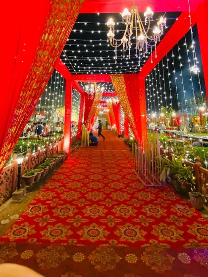 The same red walkway seen at night, with fairy lights and chandeliers creating a magical, starlit path.