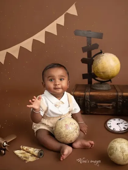 The world in his hands. This sitter-session photo shows the baby playing with a small globe, surrounded by props that evoke a spirit of travel and discovery.