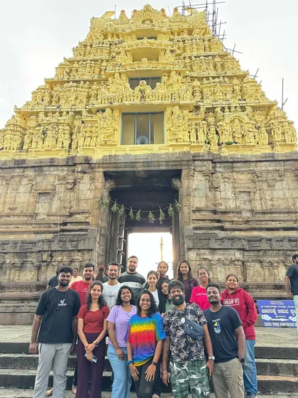 A group posing in front of the beautifully lit Chennakesava Temple at dusk. Visiting these sites at different times of day offers a unique perspective.